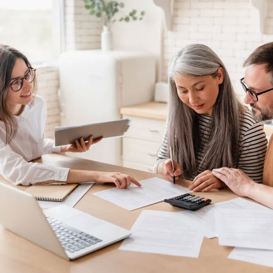 A couple sit with an administrator working out some calculations. A couple sit with an administrator working out some calculations.
